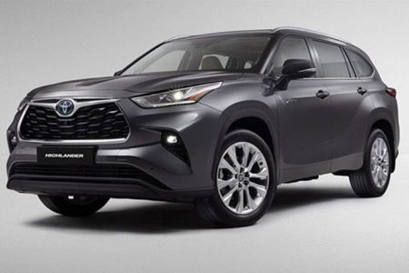 Gray Toyota Highlander SUV (side-front view), illuminated headlights, "HIGHLANDER" badge, plain light backdrop.