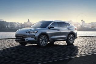 Sleek silver modern compact SUV parked outdoors at sunrise, with scenic distant buildings and soft glowing sky as backdrop