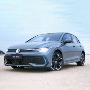 A gray Volkswagen Golf parked on a sandy area under a clear sky.