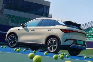 A light - colored BYD Yuan Plus electric SUV on a tennis court with tennis balls around.