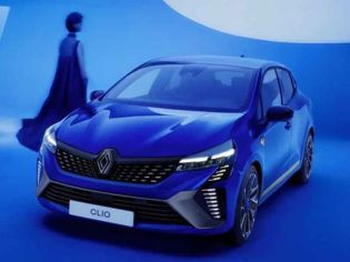 A blue Renault Clio in a blue - themed studio setting, with a person in a long dress in the background.