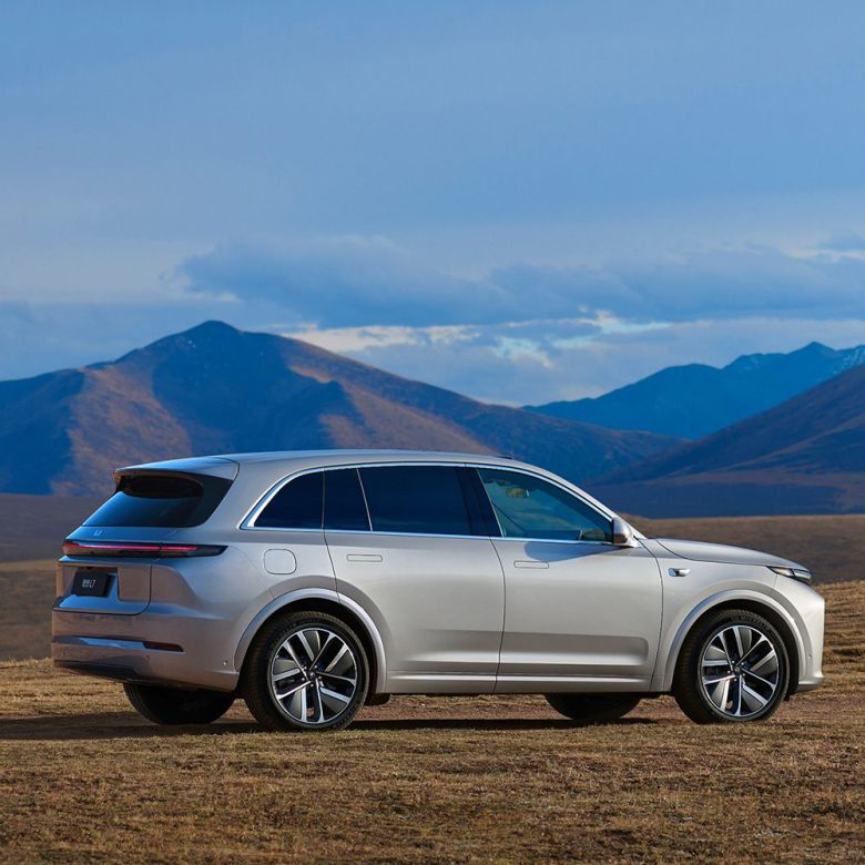 A silver SUV parked on a grassland with mountains in the background.