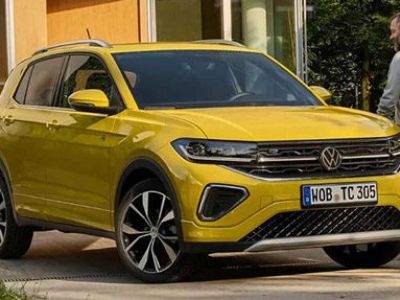 Bright yellow Volkswagen SUV (with VW logo, alloy wheels) parked by a building; a man walks beside it.