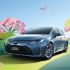 A blue Toyota Corolla Intelligent Electric Hybrid car in a scenic, spring - like setting with pink flowers and birds