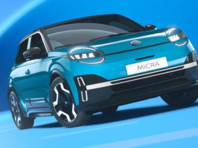 The teal Nissan Micra, with its futuristic design and bold headlights, is showcased against a vibrant blue background, highlighting its modern and dynamic aesthetic.