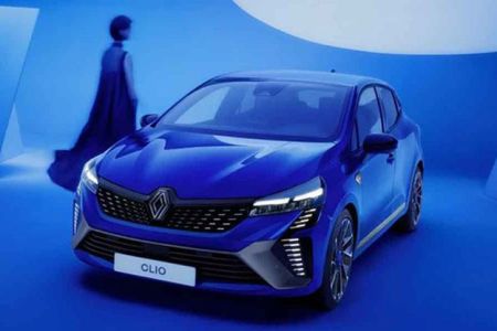A blue Renault Clio in a blue - themed studio setting, with a person in a long dress in the background.