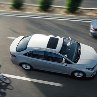 A silver corolla 2024 with a sunroof driving on the road.