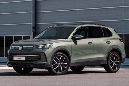 A light green Volkswagen Tiguan SUV parked in front of a modern industrial building.