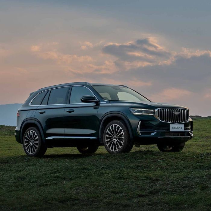 Geely Xingyue L SUV parked on a grassy field under a sunset sky.