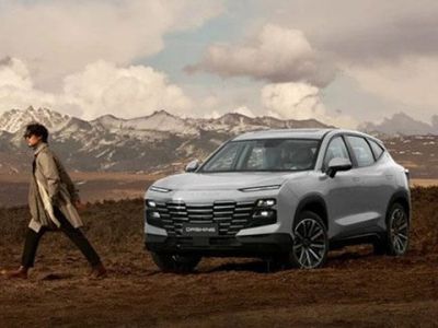 A man walks beside a white JETOUR DASHING SUV in a rugged, mountainous landscape under a cloudy sky.