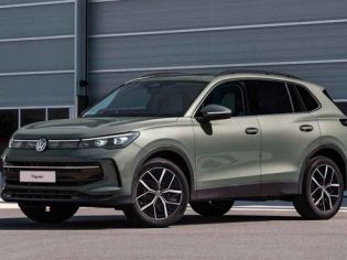 A light green Volkswagen Tiguan SUV parked in front of a modern industrial building.