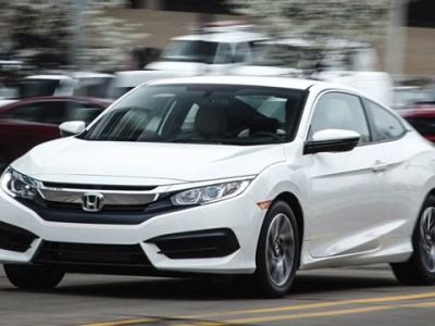 White Honda Civic Coupe: Sleek two-door coupe in motion on a city street, showcasing modern design and dynamic performance.
