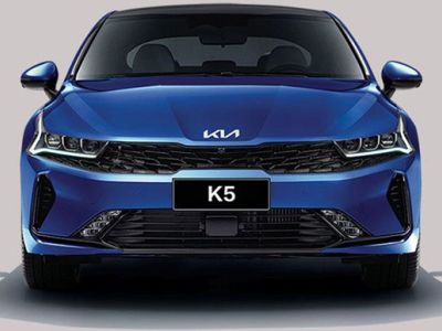 Front view of a blue Kia K5 sedan, highlighting its sleek headlight design, black grille, and "K5" badging, embodying a sporty and modern aesthetic.