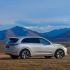 A silver SUV parked on a grassland with mountains in the background.