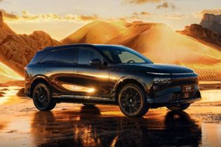 A black Xpeng G9 SUV parked in a desert landscape at sunset, with golden sand dunes and a reflective wet ground.