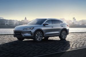 Sleek silver modern compact SUV parked outdoors at sunrise, with scenic distant buildings and soft glowing sky as backdrop