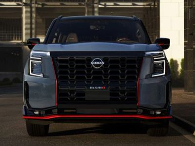 Front view of a bold Nissan pickup truck, featuring a large black V-motion grille, angular LED headlights, and striking red accent trim.