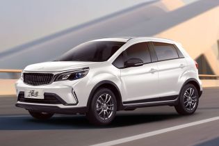 A white Suzuki X5 PRO car is driving on the road, with a modern architectural background.