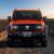 Front view of an orange off - road SUV parked on a rocky desert terrain.
