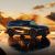 A black Xpeng G9 SUV parked in a desert landscape at sunset, with golden sand dunes and a reflective wet ground.