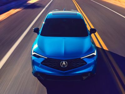 2026 Acura ADX A-Spec shown in Double Apex Blue Pearl II, driving on the road