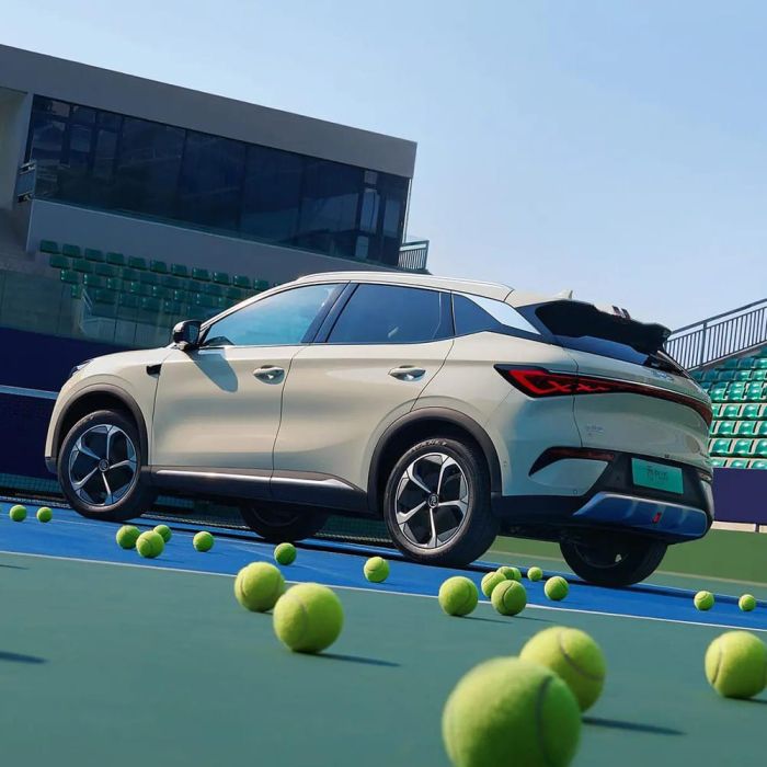 A light - colored BYD Yuan Plus electric SUV on a tennis court with tennis balls around.