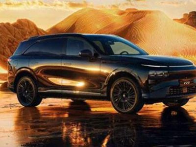 Xpeng G9 parked on reflective wet ground, set against a glowing golden desert landscape at sunset.