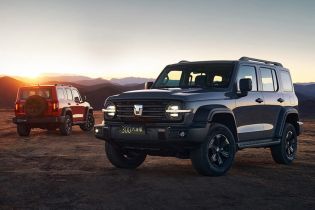 Two off - road SUVs (one gray, one red) parked on an open plain with a sunset and mountainous background.