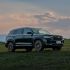 Geely Xingyue L SUV parked on a grassy field under a sunset sky.