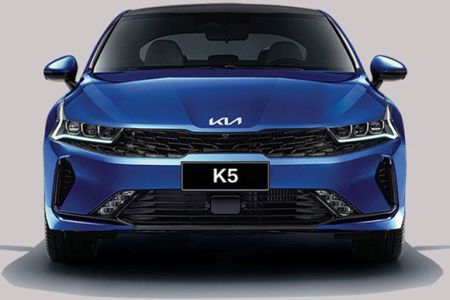 Front view of a blue Kia K5 sedan, highlighting its sleek headlight design, black grille, and "K5" badging, embodying a sporty and modern aesthetic.