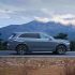 A gray SUV driving on a road with mountains in the background.