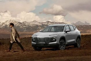 A man walks beside a white JETOUR DASHING SUV in a rugged, mountainous landscape under a cloudy sky.