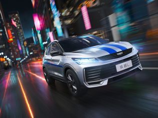 A Geely BinYue L SUV with blue stripes driving through a vibrant, neon - lit city at night.