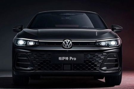 Front view of the black Volkswagen Passat Pro sedan, featuring illuminated headlights and a honeycomb grille, set against a dark background with red accents, highlighting its modern and bold design.