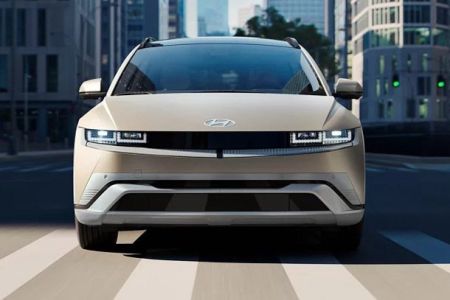 Hyundai IONIQ 5: Futuristic beige EV cruising city streets, blending sleek design with eco-friendly urban mobility.