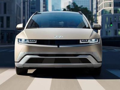 Hyundai IONIQ 5: Futuristic beige EV cruising city streets, blending sleek design with eco-friendly urban mobility.