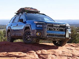Mud-streaked blue off-road Mud-streaked blue off-road SUV parked on a red rock overlook, with gear loaded on its roof rack and expansive desert views behind. parked on a red rock overlook, with gear loaded on its roof rack and expansive desert views behind.