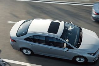 A silver corolla 2024 with a sunroof driving on the road.