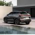 Rear view of Geely BinYue L SUV by a building and water.
