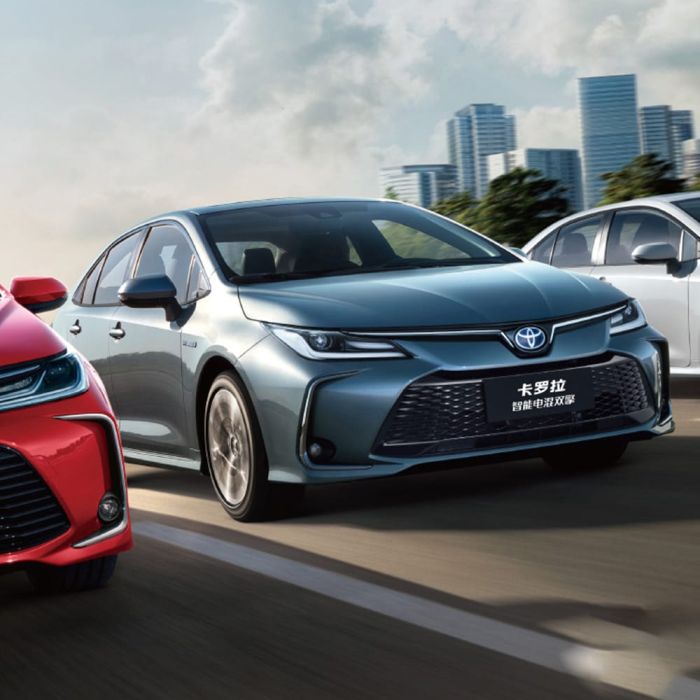 Toyota Corolla 2024 (including a gray Corolla Intelligent Electric Hybrid) driving on the road with a cityscape in the background.