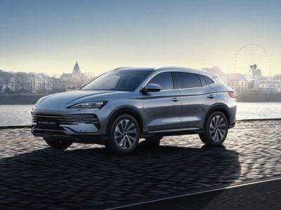 Sleek silver modern compact SUV parked outdoors at sunrise, with scenic distant buildings and soft glowing sky as backdrop