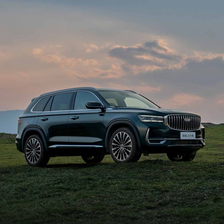 Geely Xingyue L SUV parked on a grassy field under a sunset sky.