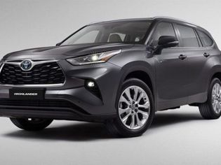 Gray Toyota Highlander SUV (side-front view), illuminated headlights, "HIGHLANDER" badge, plain light backdrop.