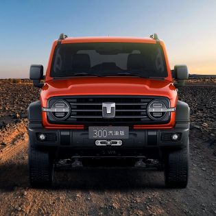 Front view of an orange off - road SUV parked on a rocky desert terrain.