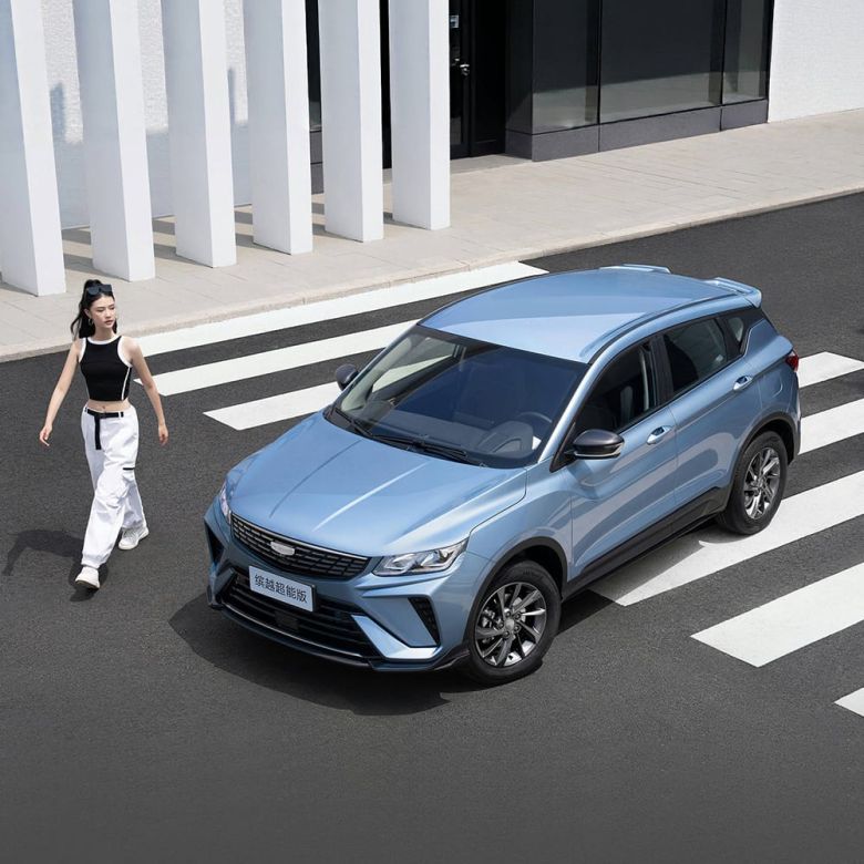 A light blue SUV parked on a crosswalk with a woman walking nearby and a modern building in the background.