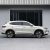 A white SUV with a sleek side profile, featuring stylish alloy wheels and a streamlined body, parked in front of a modern building with large glass windows.
