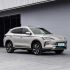 A silver BYD Song PLUS DM-i SUV parked in front of a modern building, highlighting its sleek design and stylish alloy wheels in an urban setting.
