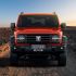 Front view of an orange off - road SUV parked on a rocky desert terrain.