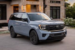Light blue 2026 Ford Expedition with black accents parked on a driveway in front of a modern stone and stucco home.