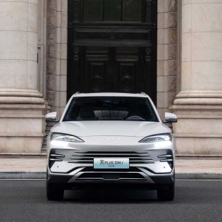 Front view of BYD Song Plus DM-i 2025 model, a silver SUV with distinctive Ocean X Face grille and sleek headlights, parked in front of a grand stone building.